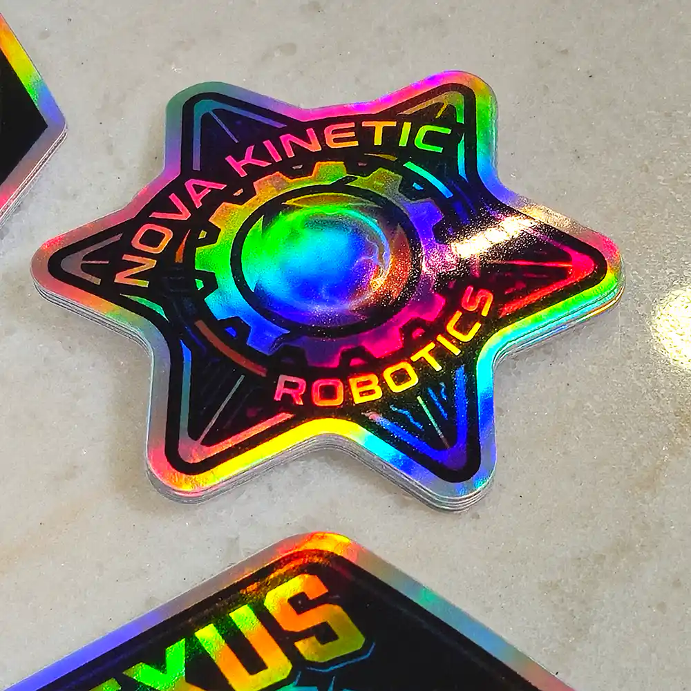 holographic-promo-stickers-3 • StickerPlanet Canada Colorful holographic star-shaped badge reading 'Nova Kinetic Robotics' with a gear in the center.