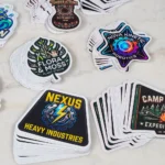 promo-stickers-5 • StickerPlanet Canada Stack of glossy stickers featuring logos: Nexus Heavy Industries, Nova Kinetic Robotics, Flora & Moss Plant Studio, and Timber & Tone Instruments.